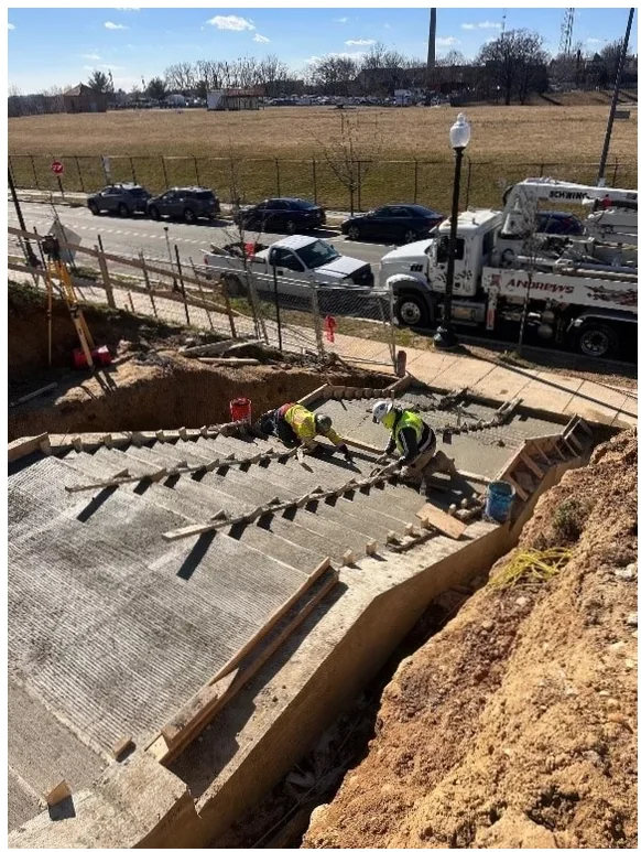 Barry Farm 1A — crew members finishing concrete stairs on grade with formwork and reinforcing in place.