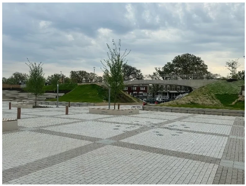 McMillan Community Center — finished plaza paving with arched pedestrian bridge in the background.