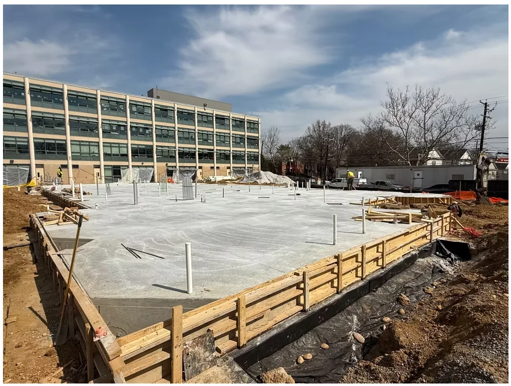 Leckie Elementary School — freshly poured slab on grade with perimeter formwork and column dowels in place.